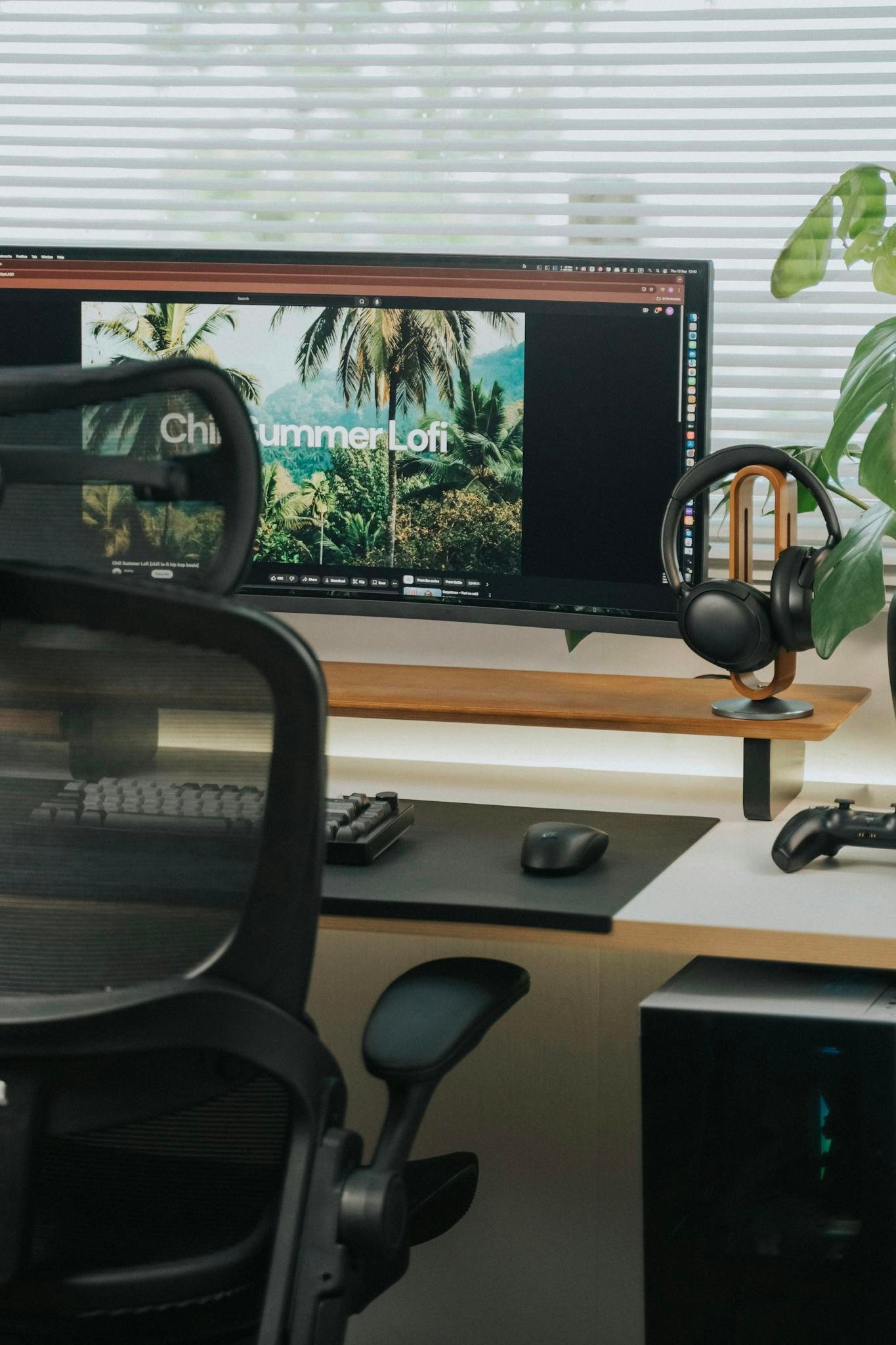Sleek home office desk with chair, monitor, and headphones in natural light.