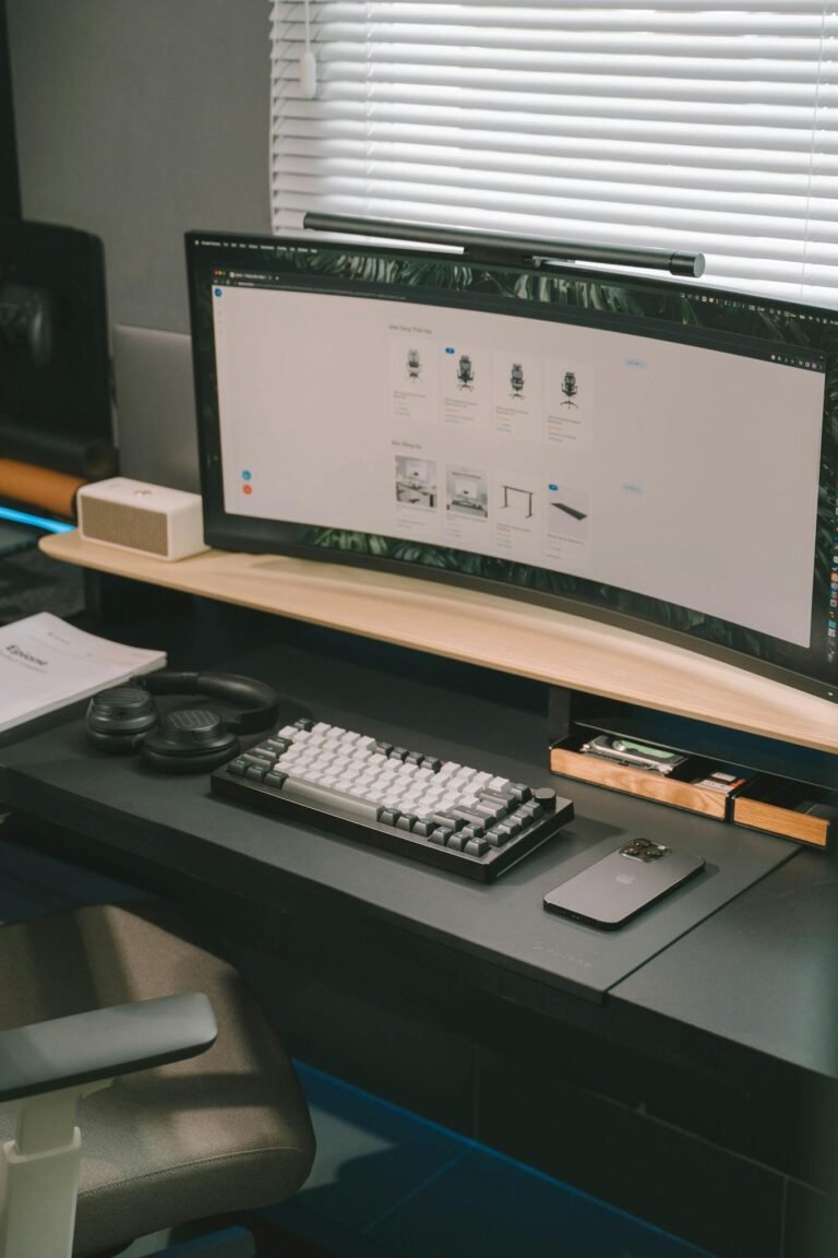 Stylish and organized home office desk setup with a curved monitor, keyboard, and tech accessories.